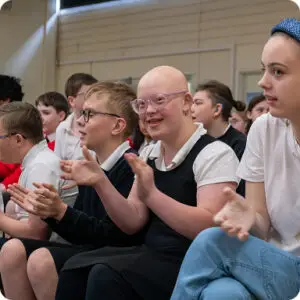 Students enthusiastically clapping during a school event in a classroom setting, expressing joy and engagement.