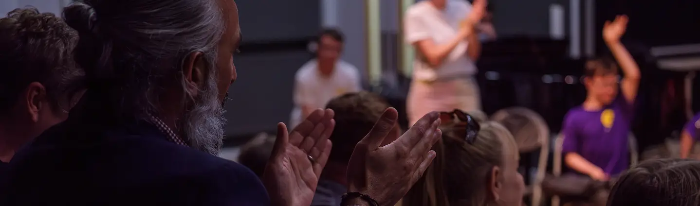 Audience applauding during a performance in a theater setting.