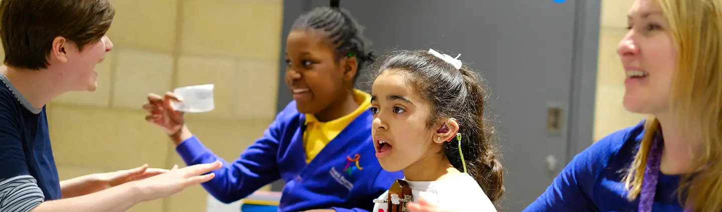 Children and adults engaging in a cheerful sign language conversation at a classroom table.