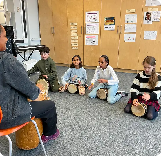 Children participate in a percussion class, learning to play drums in a bright classroom environment.