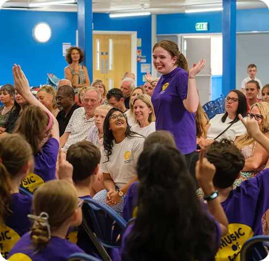 Students in purple shirts engage with the audience during a lively classroom presentation.